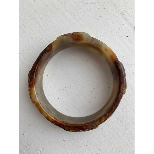 22 - A Chinese carved jade bangle, probably Neolithic period. With russet inclusions, carved with opposin... 