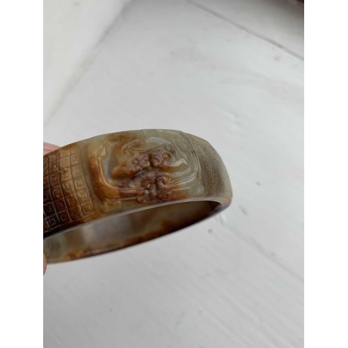 22 - A Chinese carved jade bangle, probably Neolithic period. With russet inclusions, carved with opposin... 