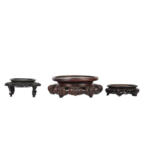 237 - Eight Chinese carved wood vase stands. Largest inner diameter 15cm and a folding plate stand. (9)