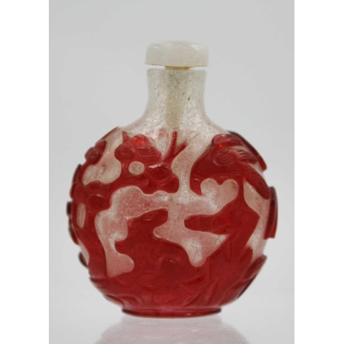 244 - A Chinese red overlay glass snuff bottle. With hardstone stopper, the body depicting horses below wi... 