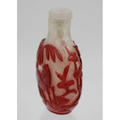 244 - A Chinese red overlay glass snuff bottle. With hardstone stopper, the body depicting horses below wi... 