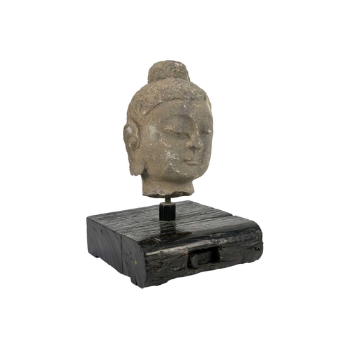 293 - A carved stone Buddha head. Mounted on a wooden plinth base, height of head 20cm, width 12.5cm, dept... 