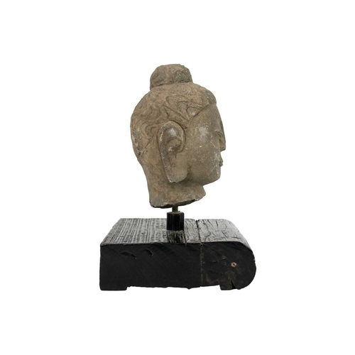 293 - A carved stone Buddha head. Mounted on a wooden plinth base, height of head 20cm, width 12.5cm, dept... 