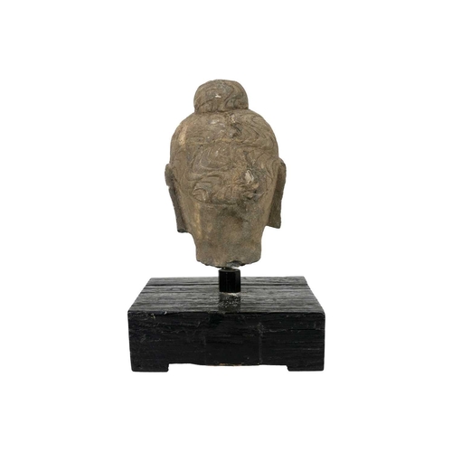 293 - A carved stone Buddha head. Mounted on a wooden plinth base, height of head 20cm, width 12.5cm, dept... 