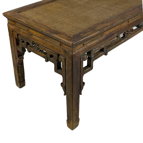 323 - A Chinese hardwood Kang table, early 20th century. The rattan covered top, above a pierced frieze on... 