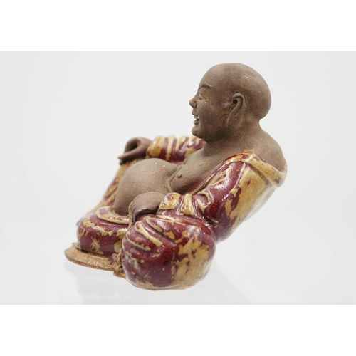 352 - A Chinese pottery model of Buddha, 18th/19th century. The smiling Buddha in a large robe and reclini... 