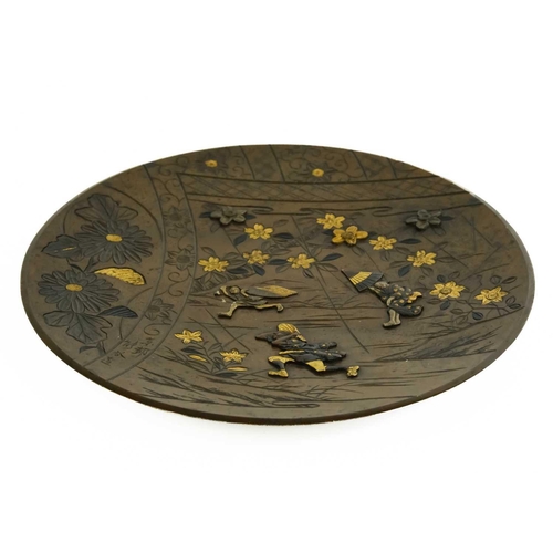 465 - A Japanese bronze shakudo plate, Meiji period. Decorated with raised figures and engraved foliage, d... 