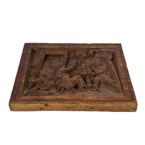 177 - A carved oak plaque. Depicting two topers in a rustic tavern, initial JMR, 20.5X26cm, a label states... 