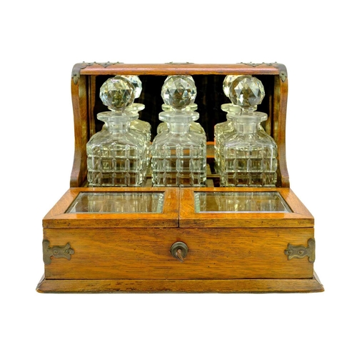 180 - A late Victorian oak tantalus and cigar cabinet. Fitted three cut glass decanters and stoppers, with... 