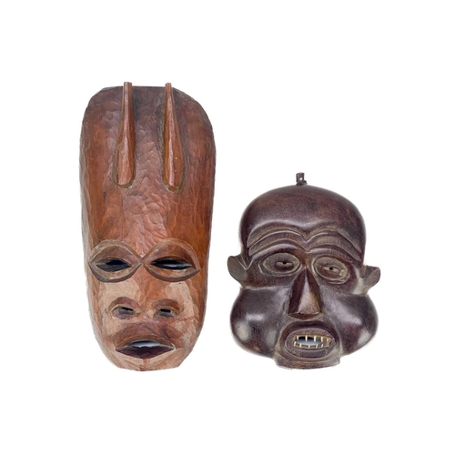 194 - An African carved wood carved mask. Probably Cameroon, with bone teeth, inflated cheeks and remnants... 