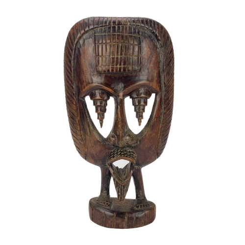 194 - An African carved wood carved mask. Probably Cameroon, with bone teeth, inflated cheeks and remnants... 