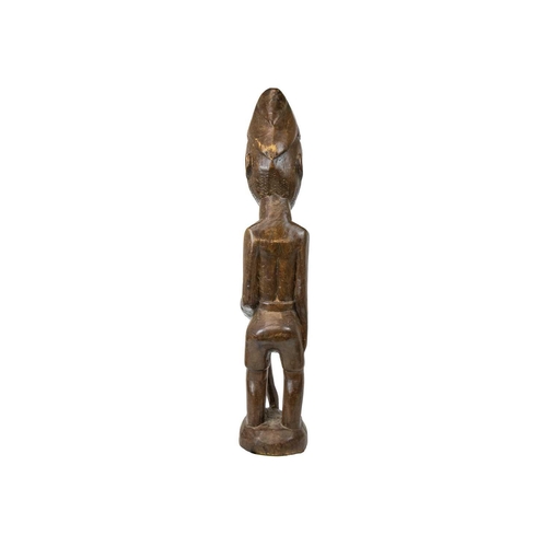 215 - A large African wood carved standing figure. Modelled holding a snake, height 84cm. Maurice Jenkins ... 