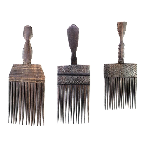 223 - Three African carved hardwood combs, each with a carved mask handle. 21cm, 21cm and 18cm.