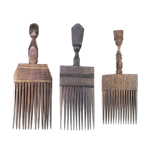 223 - Three African carved hardwood combs, each with a carved mask handle. 21cm, 21cm and 18cm.