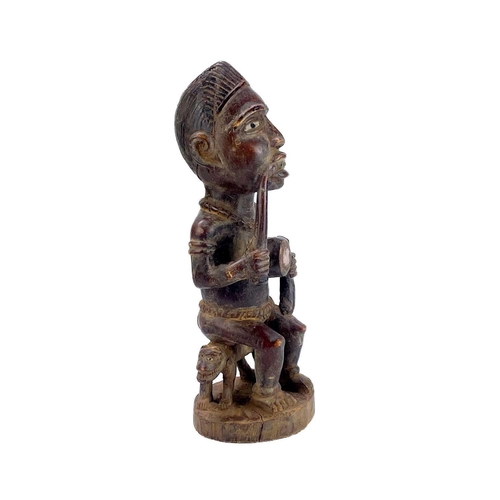 237 - A good wood carved figure possibly Zaire Bembe. The male figure with glass eyes seated on a two head... 