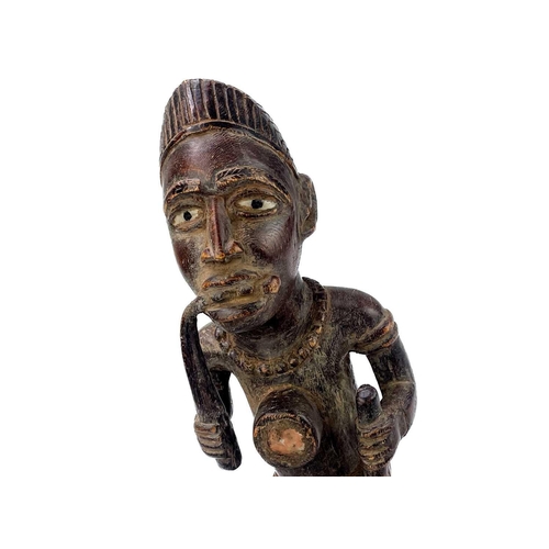 237 - A good wood carved figure possibly Zaire Bembe. The male figure with glass eyes seated on a two head... 