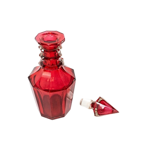 346 - A 19th century ruby glass decanter. With facet cut body and triple ring neck, and faceted conical st... 