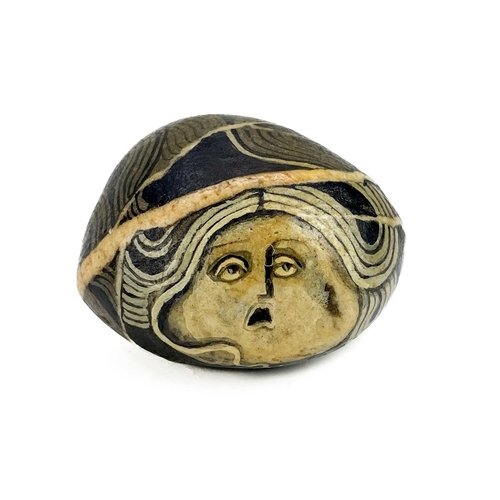 42 - Irene Jones (1938) A pebble painted with a female mask, signed and dated '74, length 5cm, together w... 