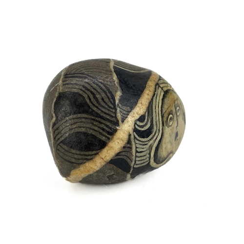 42 - Irene Jones (1938) A pebble painted with a female mask, signed and dated '74, length 5cm, together w... 