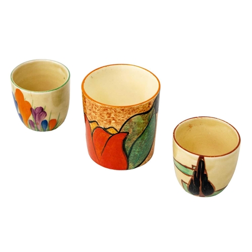 425 - A Clarice Cliff Red Trees & House pattern egg cup. Height 4cm, together with Clarice Cliff Cafe au L... 