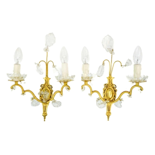 477 - A pair of gilt metal twin branch wall lights. 20th century, with cut glass shell, spear and pendant ... 