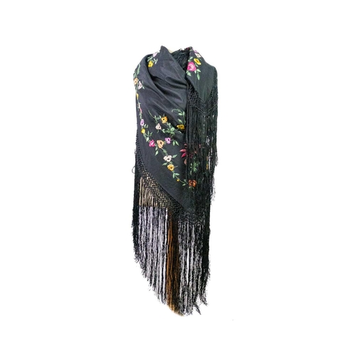 506 - A silk piano shawl. The black ground embroidered with colourful flowers and foliage with outer knott... 