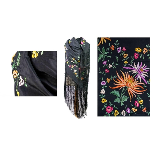 506 - A silk piano shawl. The black ground embroidered with colourful flowers and foliage with outer knott... 