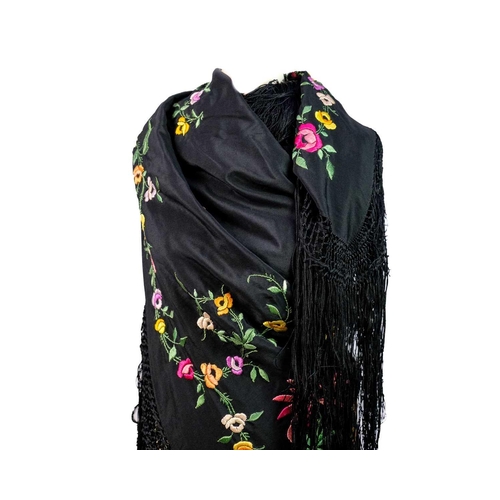 506 - A silk piano shawl. The black ground embroidered with colourful flowers and foliage with outer knott... 