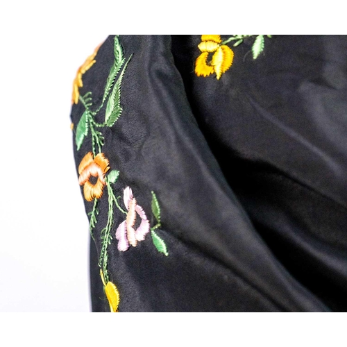 506 - A silk piano shawl. The black ground embroidered with colourful flowers and foliage with outer knott... 