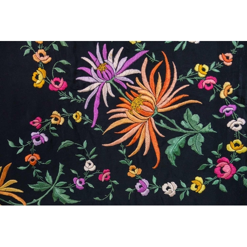 506 - A silk piano shawl. The black ground embroidered with colourful flowers and foliage with outer knott... 