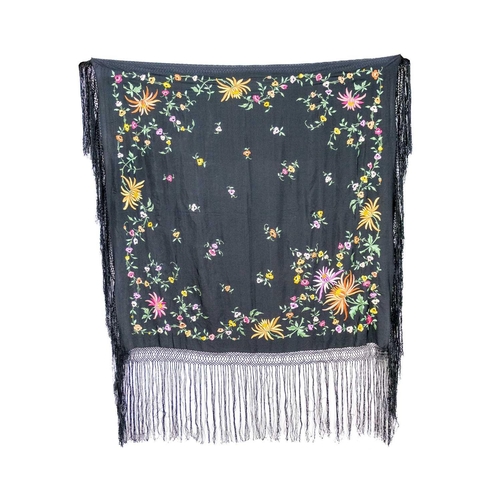 506 - A silk piano shawl. The black ground embroidered with colourful flowers and foliage with outer knott... 