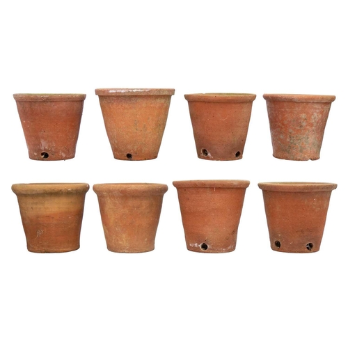 540 - Eight hand thrown terracotta plant pots. Each approximately 23cm tall. Most with chips to the bases ... 