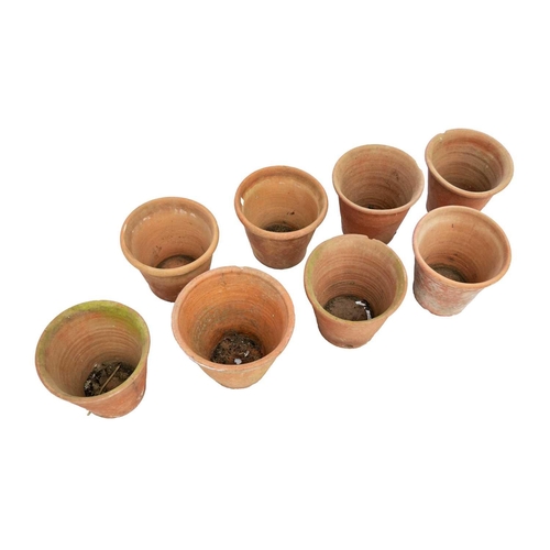 540 - Eight hand thrown terracotta plant pots. Each approximately 23cm tall. Most with chips to the bases ... 