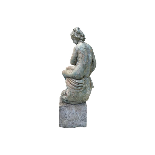 543 - A green painted garden statue of a seated female nude. Raised on associated plinth. Overall height 8... 