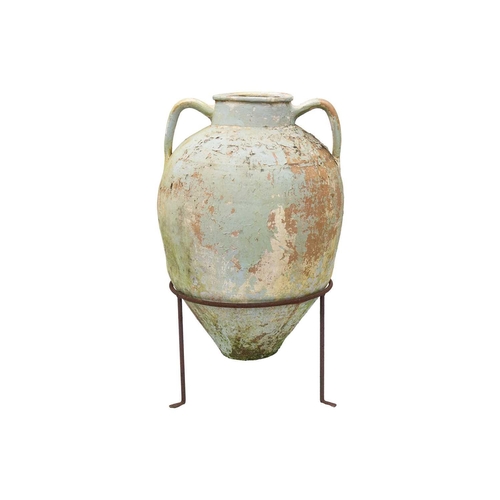 553 - A twin handled terracotta olive jar, with traces of cream and green paint. Raised on metal stand. He... 