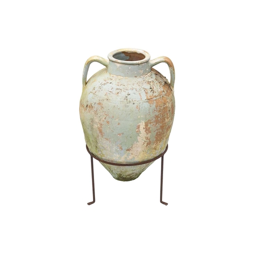 553 - A twin handled terracotta olive jar, with traces of cream and green paint. Raised on metal stand. He... 