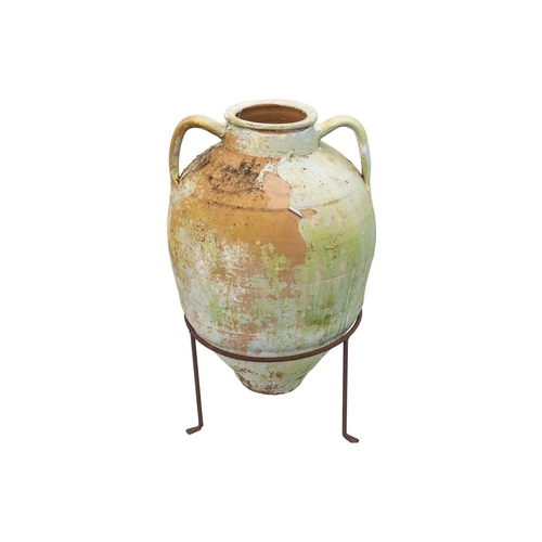 553 - A twin handled terracotta olive jar, with traces of cream and green paint. Raised on metal stand. He... 