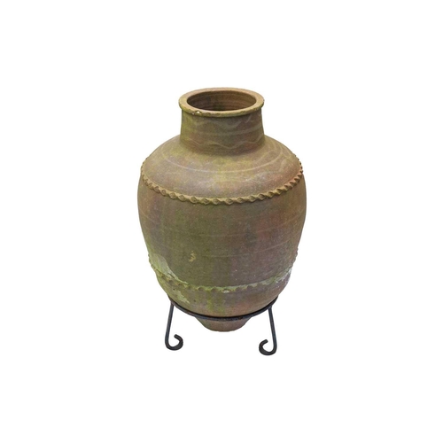 557 - A terracotta olive jar, with two bands of applied decoration, raised on metal stand. Height 70cm (in... 