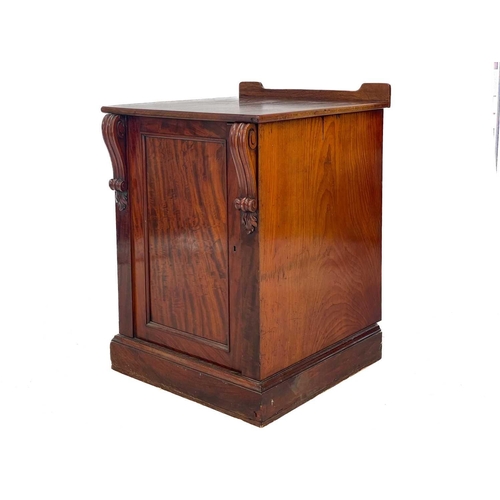 583 - A Victorian mahogany pedestal cupboard. The door with volute scroll mounts, opening to a drawer and ... 