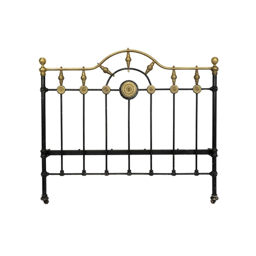 594 - A late Victorian brass and iron double bedstead. The arched foot and head with applied brass florett... 