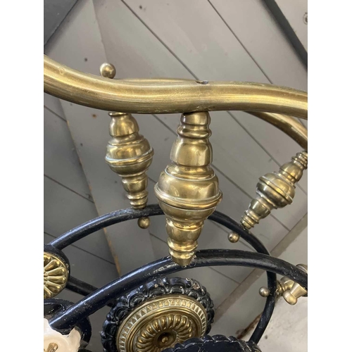 594 - A late Victorian brass and iron double bedstead. The arched foot and head with applied brass florett... 