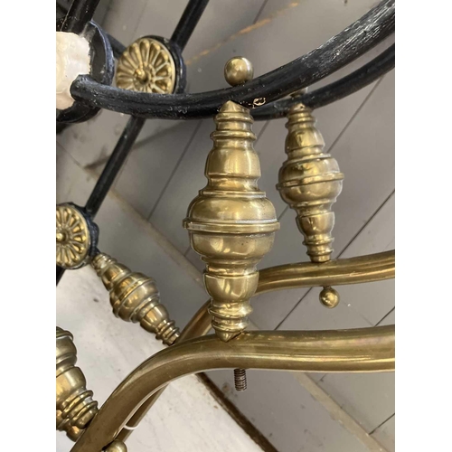 594 - A late Victorian brass and iron double bedstead. The arched foot and head with applied brass florett... 