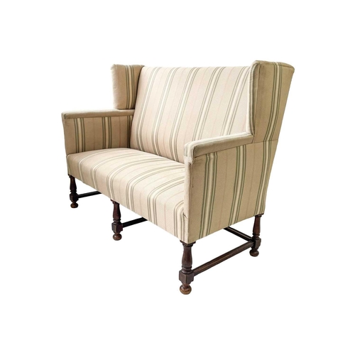 645 - A late Victorian mahogany frame winged back upholstered settee. Height 108cm width 140cm depth 70cm.