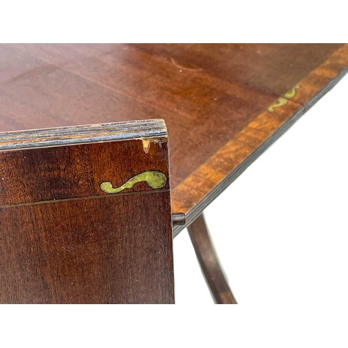 651 - A Regency style brass inlaid mahogany D-end dining table. The cross-banded edges with brass stringin... 