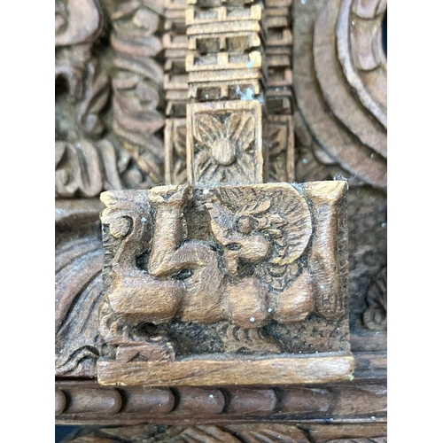 66 - An Indian hardwood panel. 20th century, intricately carved with a peacock, figures and dragons, widt... 