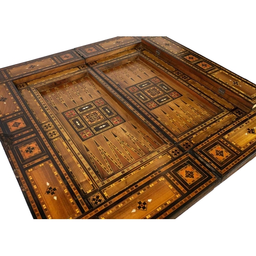 103 - A Syrian inlaid parquetry games table, 19th century. The swivel fold over top with a folding baize l... 