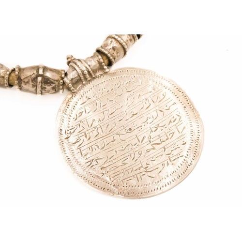 104 - An Omani silver amulet with four coins. With rows of inscription, full length 39cm, diameter 7.5cm.