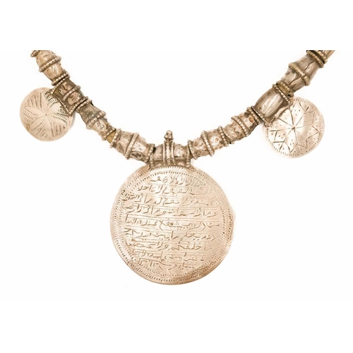 104 - An Omani silver amulet with four coins. With rows of inscription, full length 39cm, diameter 7.5cm.