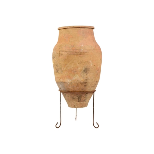 118 - A terracotta olive jar on metal stand. Height 79cm, width 35cm.