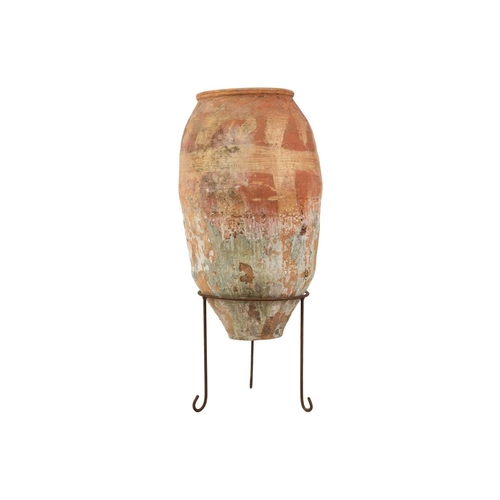 120 - A terracotta olive jar on metal stand. Height 82cm, width 32cm.